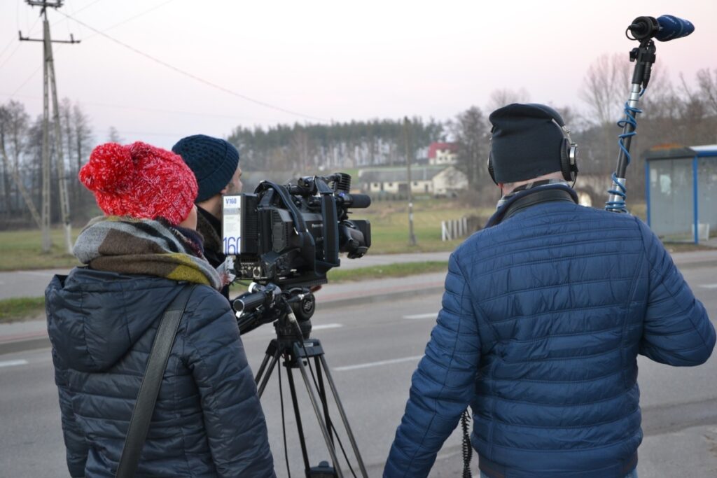 Film crew with equipment on location assisted by fixer